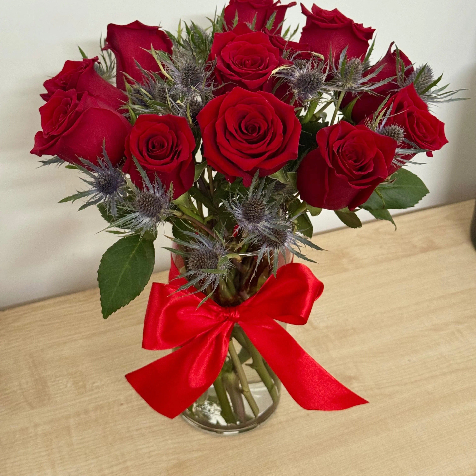 Florero con 12 rosas rojas y eringíos